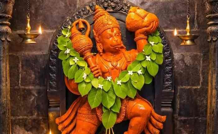 भगवान हनुमान की तस्वीर के साथ हनुमान चालीसा का पाठ करते हुए भक्त, जो सुरक्षा और सकारात्मक ऊर्जा का प्रतीक है