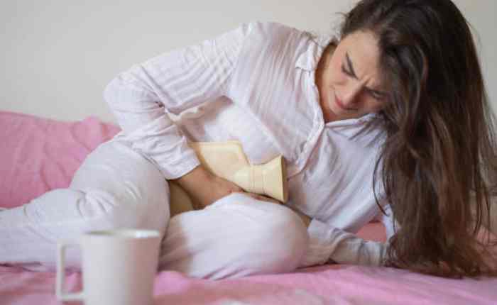 पीरियड्स के दौरान थकान और कमजोरी महसूस करती महिला, हेल्दी डाइट और आराम से राहत पाने की कोशिश