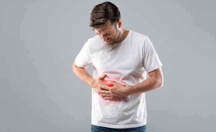 थका हुआ व्यक्ति पेट के दाईं ओर दर्द पकड़े हुए, लिवर का चेतावनी का संकेत, जो बार-बार लिवर इंफेक्शन और कैंसर के खतरे की ओर इशारा करता है.